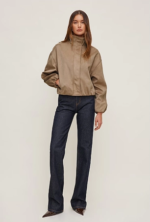 Model is wearing a tan faux suede jacket and dark wash bootcut jeans.