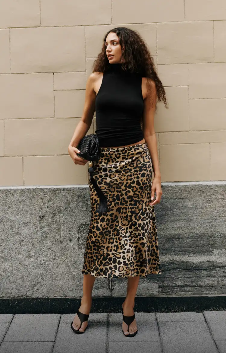 Model is wearing a black sleeveless turtleneck with a brown leopard print midi skirt.