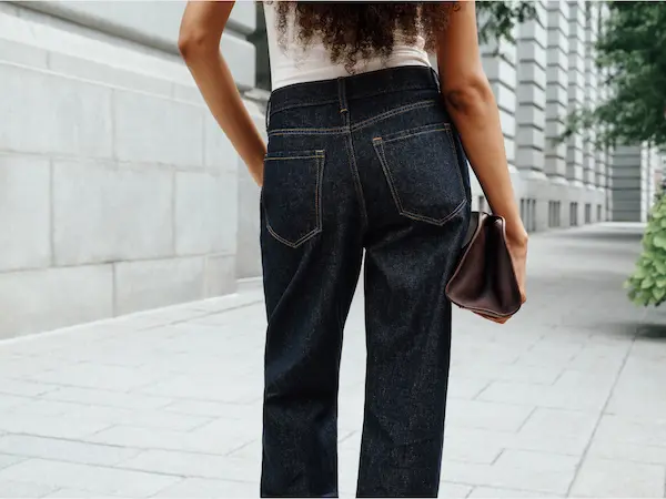 Model is wearing dark wash jeans.
