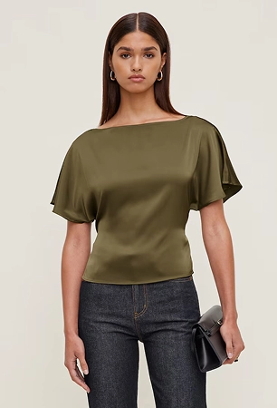 La mannequin porte une blouse en satin kaki et un jean ajusté foncé.